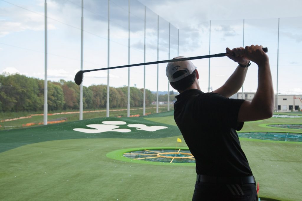 Golfer taking a swing at Topgolf in Tualatin Valley