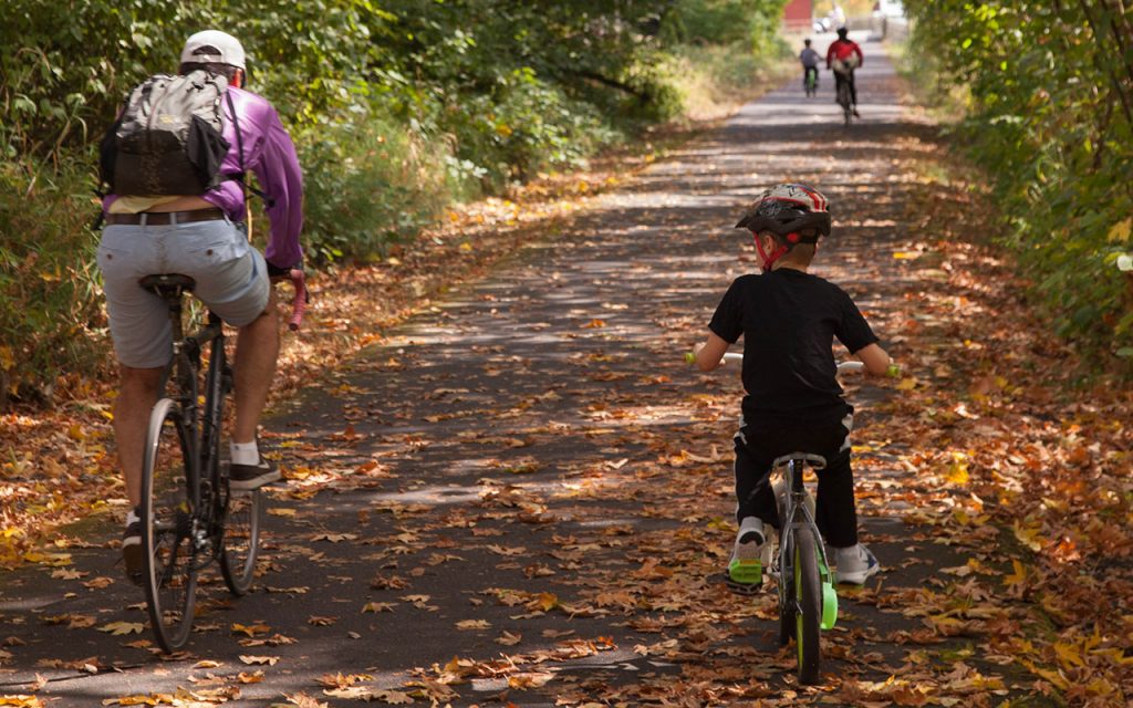 man and boy bicycling on fall leaves in Oregon