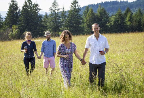 two couples walking in a field enjoying wine