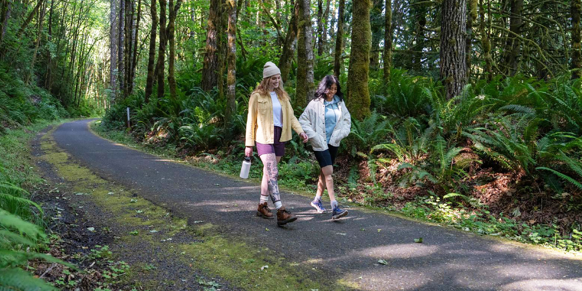 two ladies walking on a trail in the woods