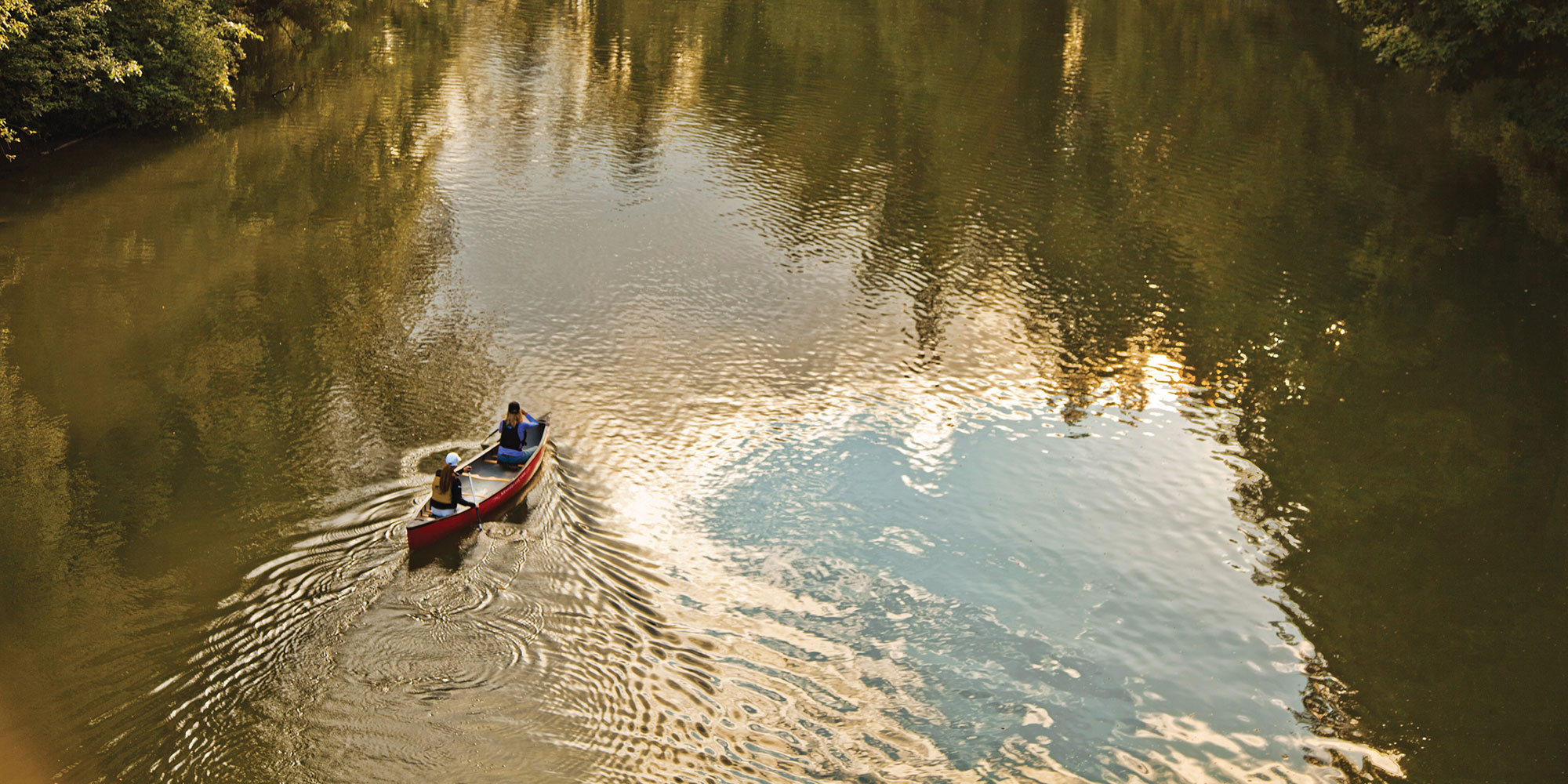 couple padding down the river in a canoe