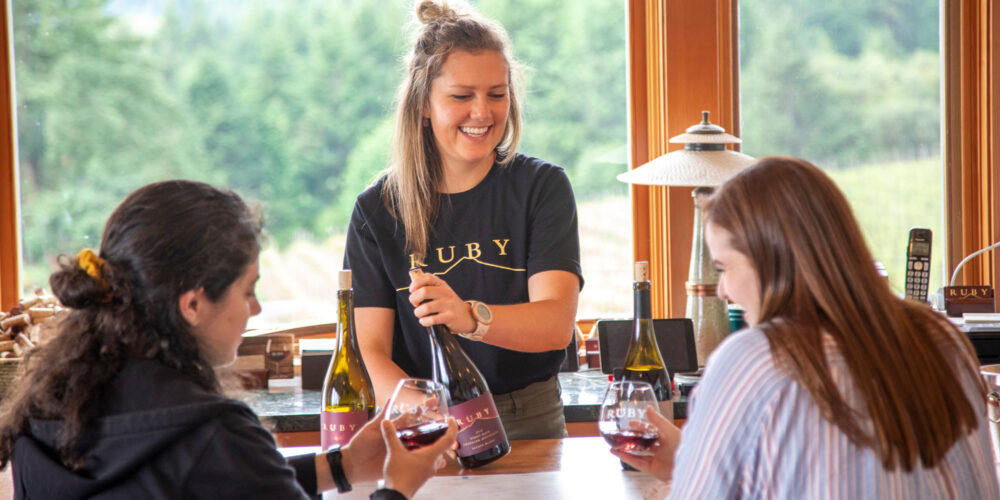 two customers enjoying an explanation of a wine from another woman