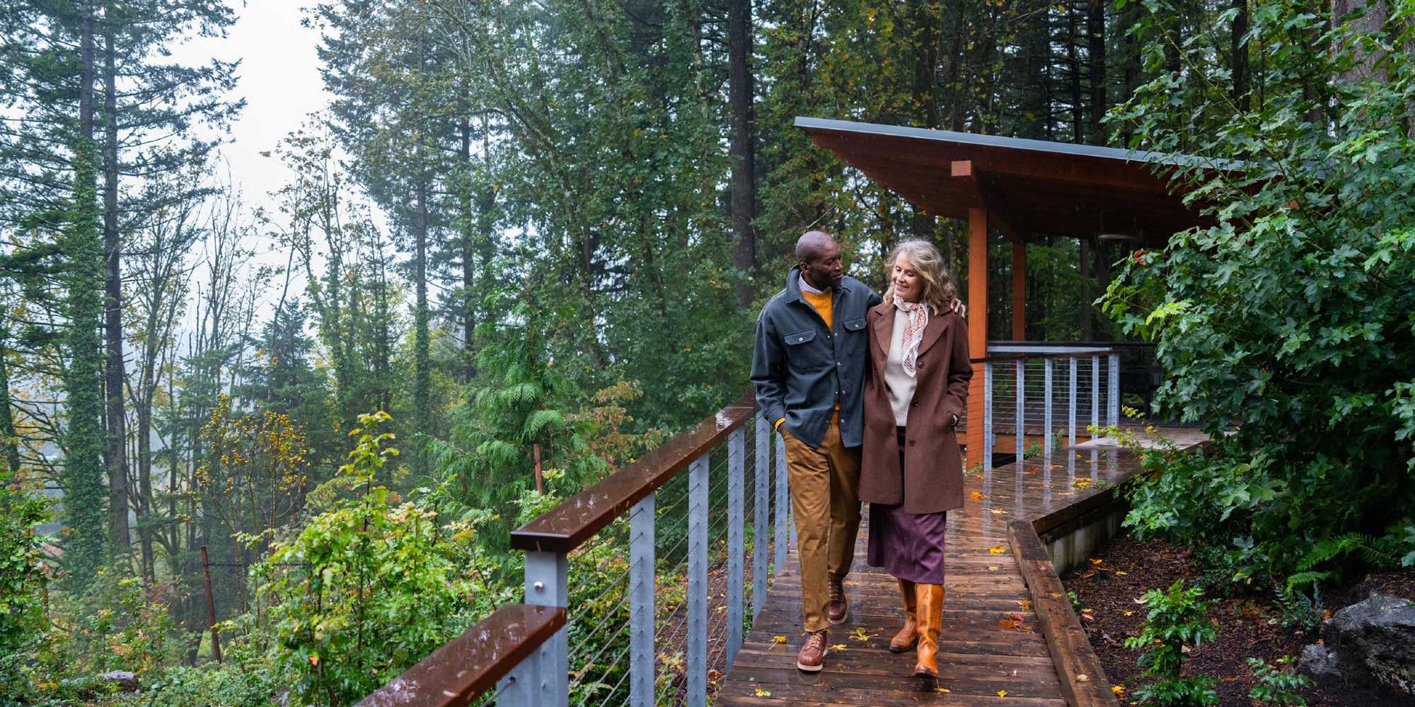 couple walking on a boardwalk in a light rain