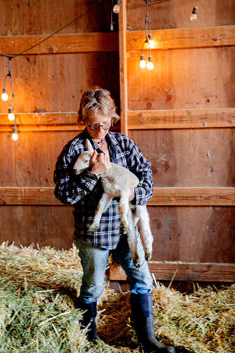 ELizabeth "Lise" Bueschen Monahan of Fraga Farmstead Creamery image of a woman with a baby goat in a barn